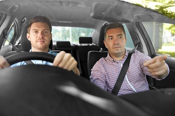 Man learning to drive with instructor telling him the next turn